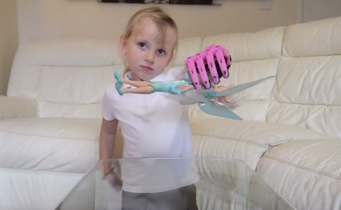 Hayley Fraser picks up her Barbie with her new pink 3D printed prosthetic hand.