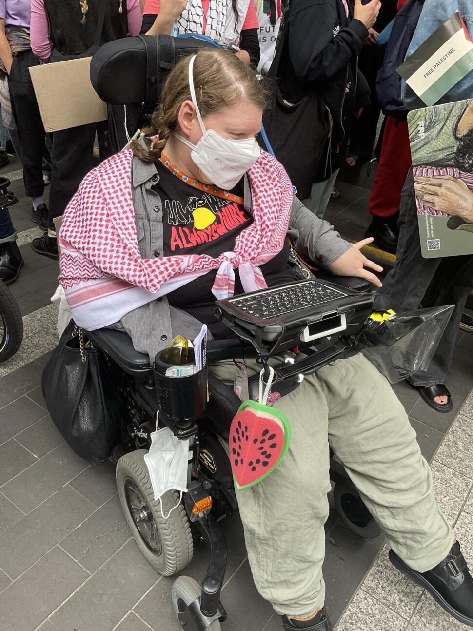 Sam Petersen sitting in her power wheelchair is wearing a mask