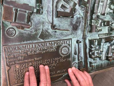 Close up photo of Carleeta's hands touching the tactile map of York, with Braille.