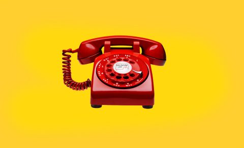 A red rotary phone on a yellow background