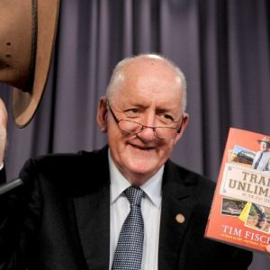 Tim Fischer smiling, with an Akubra in one hand and a book on trains in the other.